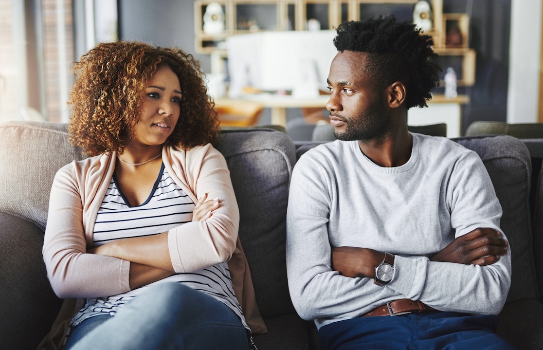 Inheritance: A couple sits on the sofa and looks at each other in annoyance.